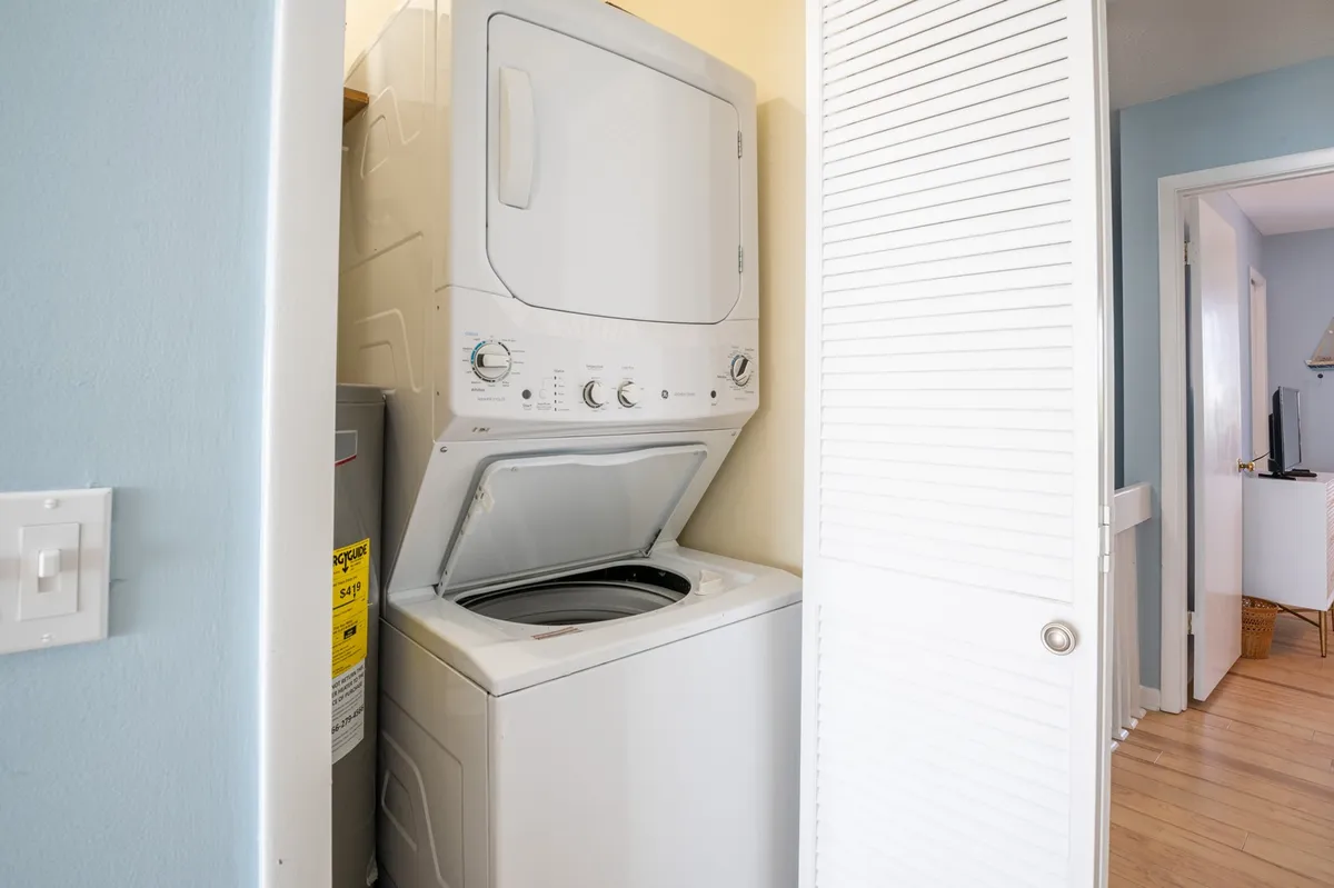 A compact laundry area featuring a stacked washer and dryer unit behind a sliding door. The space is clean and functional, suggesting the convenience of in-unit laundry without taking up significant living space.