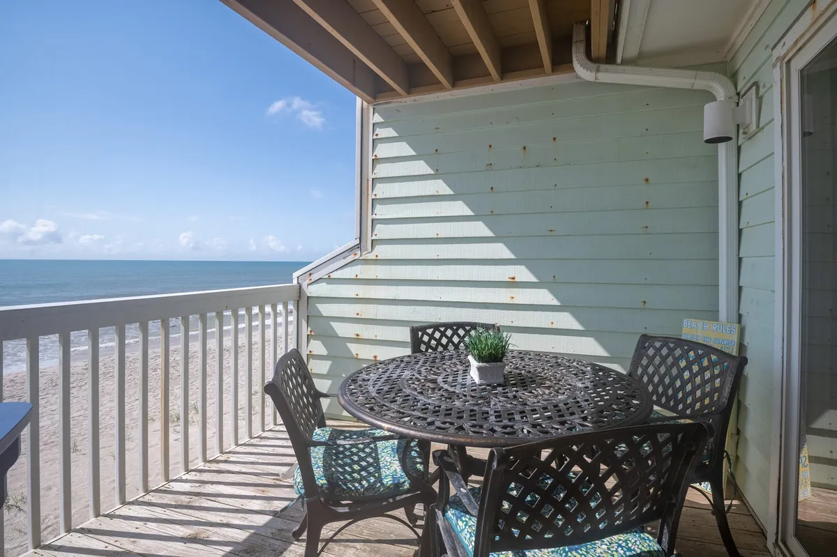 A serene outdoor setting featuring a round table and comfortable chairs on a balcony, overlooking a stunning, unobstructed ocean view. The scene conveys tranquility, with the ocean stretching out toward the horizon, making it an ideal spot for enjoying breakfast, reading, or simply soaking in the sunrise or sunset.