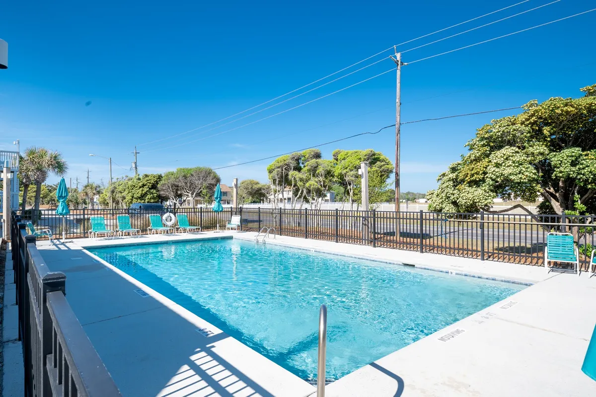 This exterior image captures a sparkling swimming pool surrounded by lush green foliage and inviting lounge chairs. The setting is relaxed, with open space for sunbathing, swimming, and socializing. The pool area gives a clear impression of the resort's leisure and recreation amenities that guests can enjoy after a day of adventure.