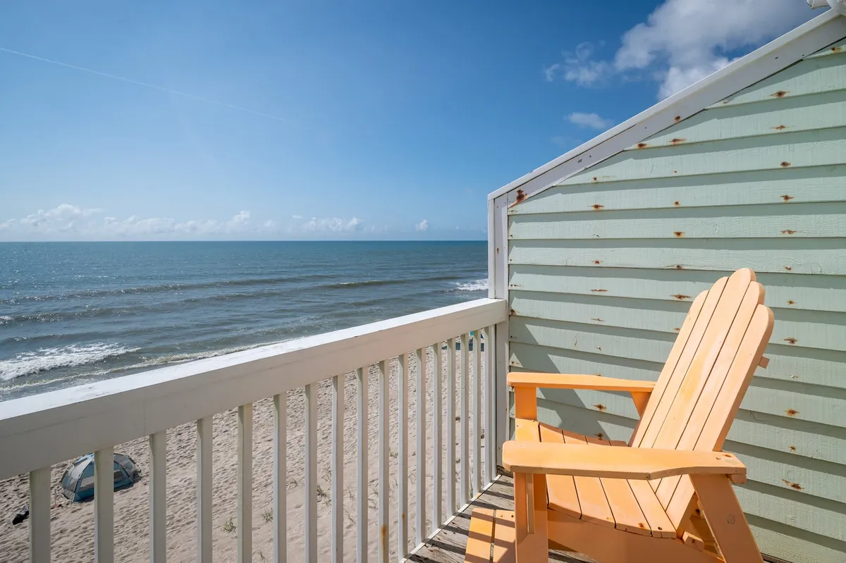 An inviting upper-level deck with an Adirondack chair overlooking the vast ocean and an open blue sky. The peaceful setting is ideal for sipping morning coffee or relaxing at sunset while soaking in breathtaking views.